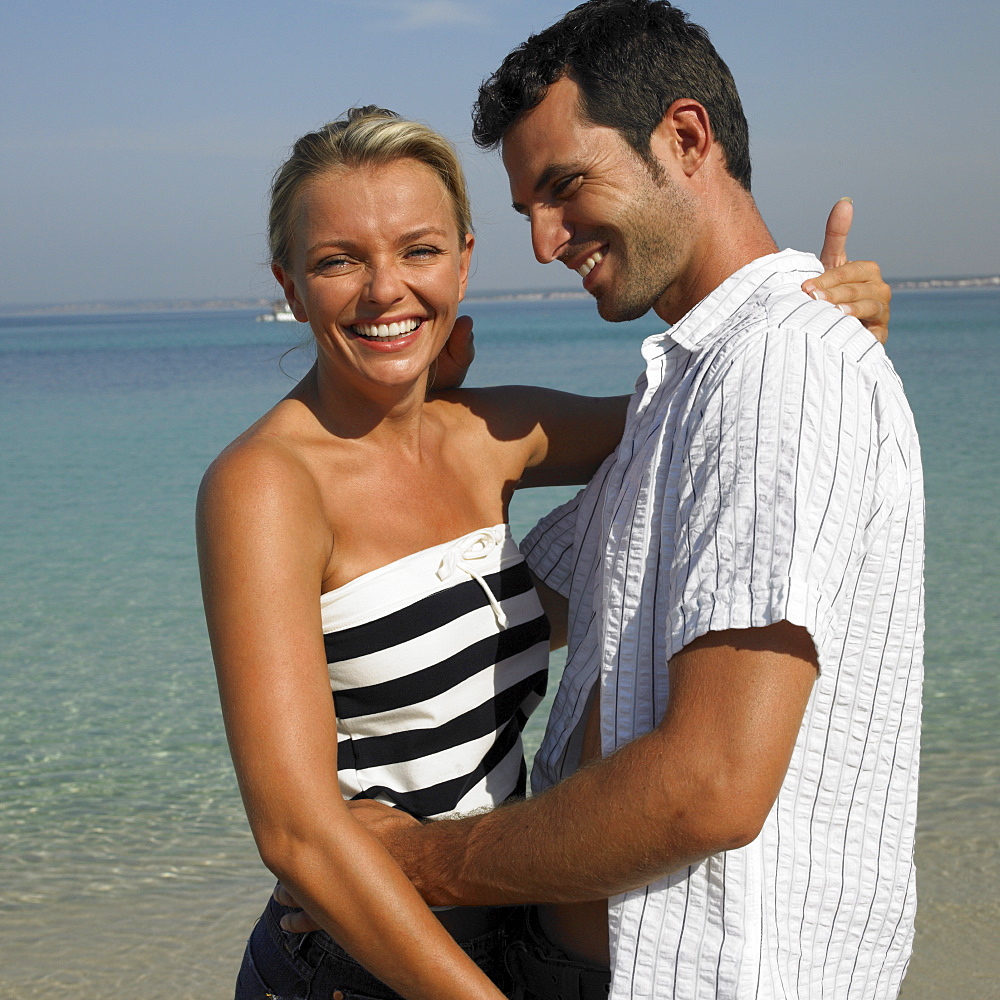 Couple embracing on beach, smiling