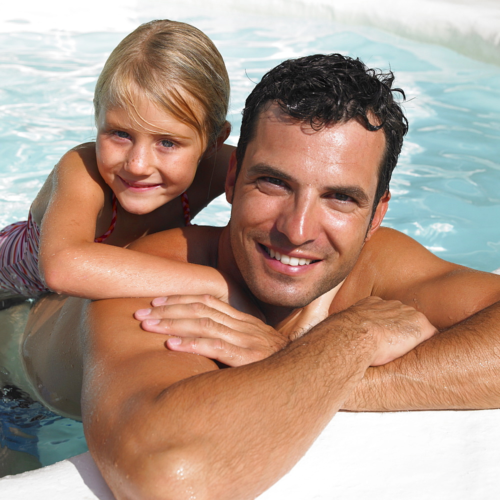 Father and daughter (6-8) in swimming pool