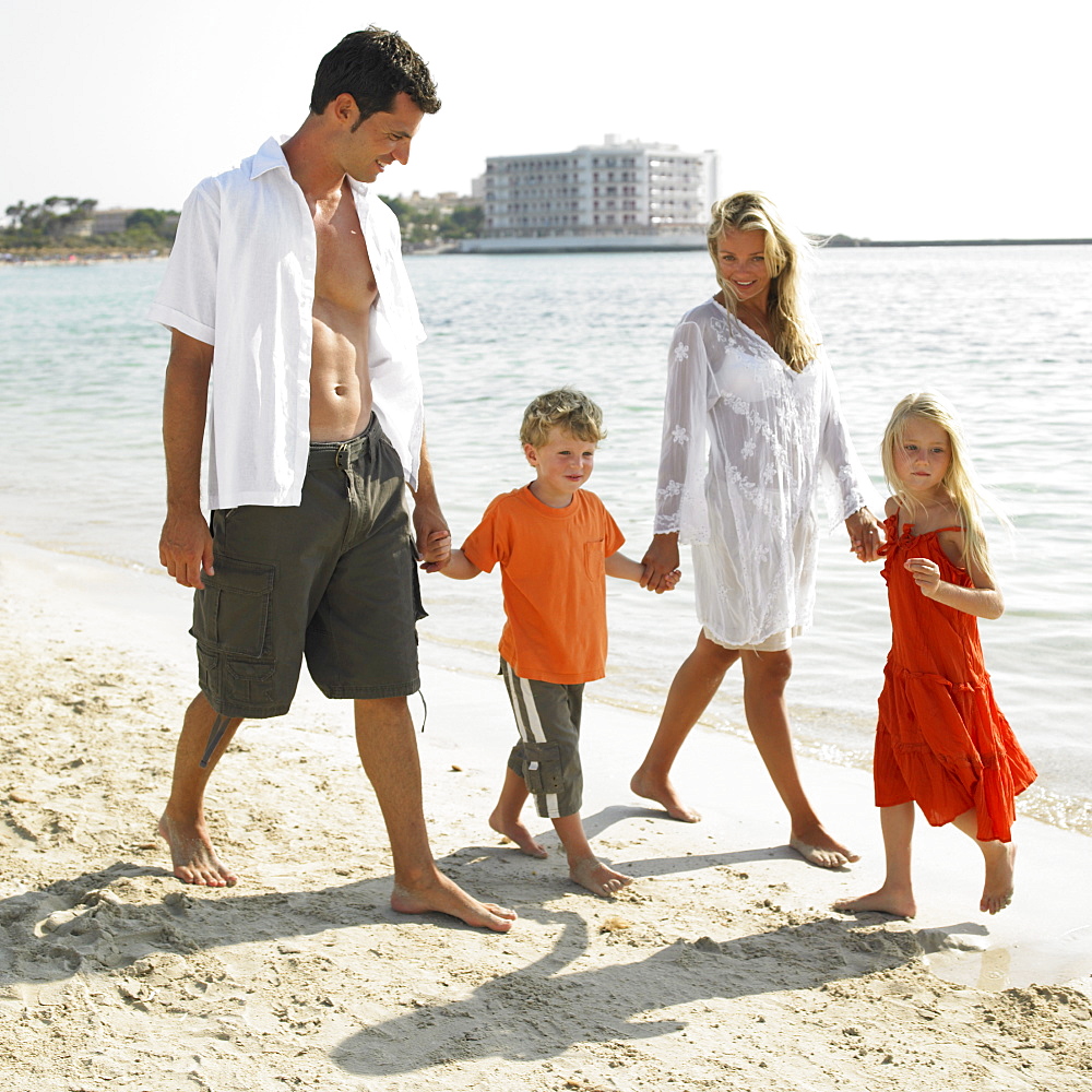 Parents and children (6-8) walking on beach