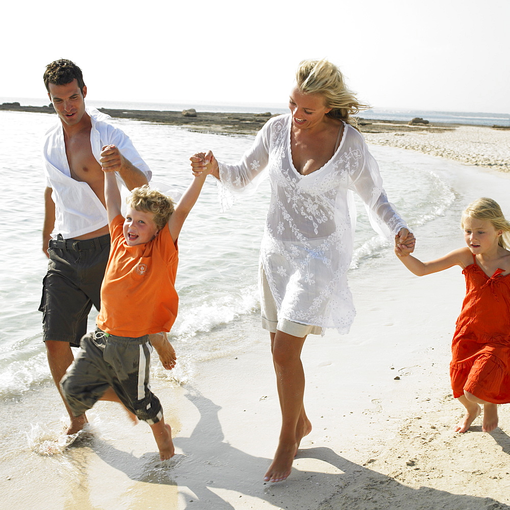 Parents and children (6-8) walking on beach