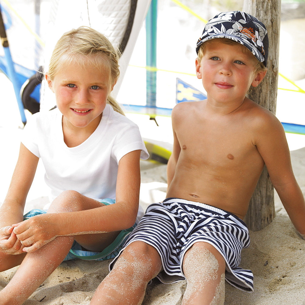 Boy and girl (6-8) on beach by windsurfer