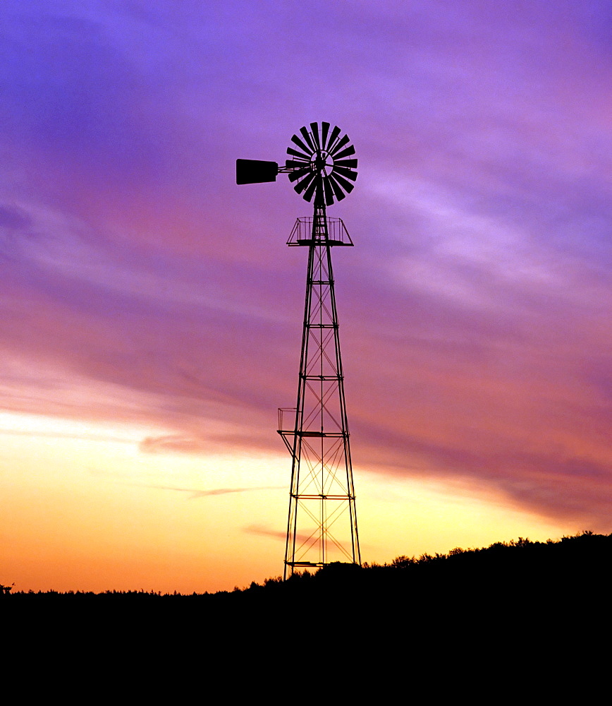 Wind pump silhouetted against colourful night sky