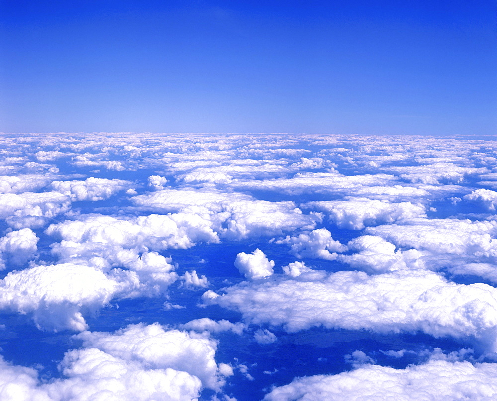 Cumulus clouds in a blue sky viewed from airplane window