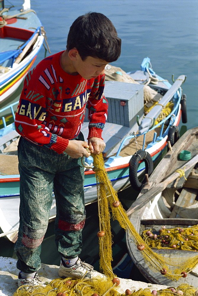 Boy in red jumper holding fishing net at Elounda near Agios Nikolas on the island of Crete, Greece, Europe