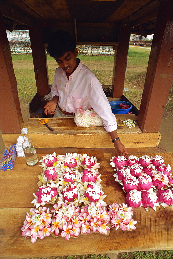 Young man selling offerings at the Temple of the Tooth, Kandy, Sri Lanka, Asia