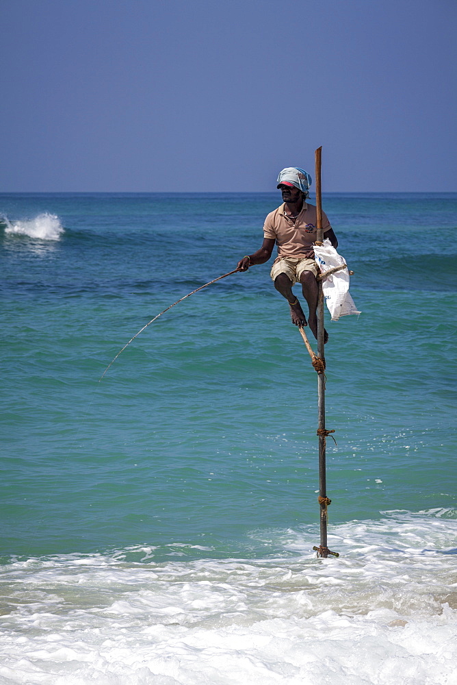 Stilt fisherman using traditional fishing techniques on a wooden pole, Weligama, Sri Lanka, Indian Ocean, Asia 