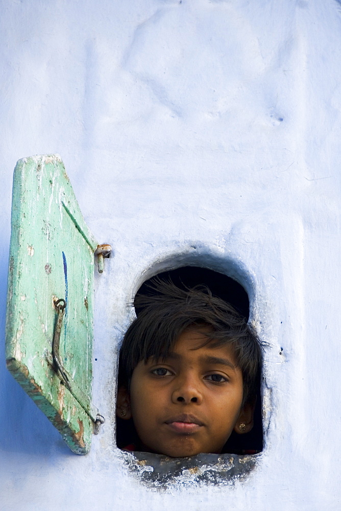 Young boy looking through small window, Udaipur, Rajasthan, India