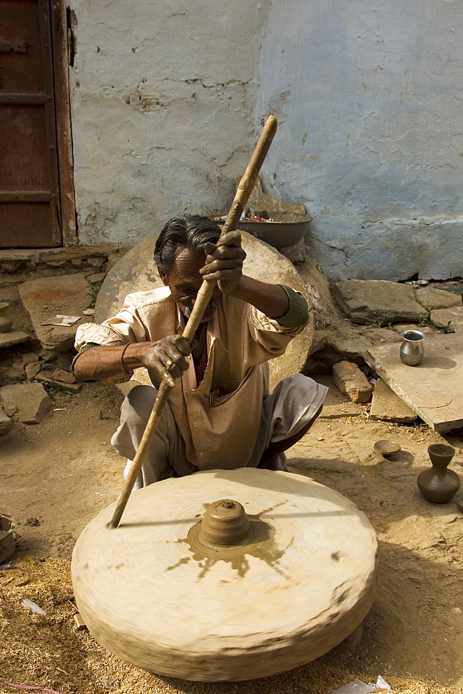 Potter creating clay pots on a manual stone wheel, Udaipur, Rajasthan, India