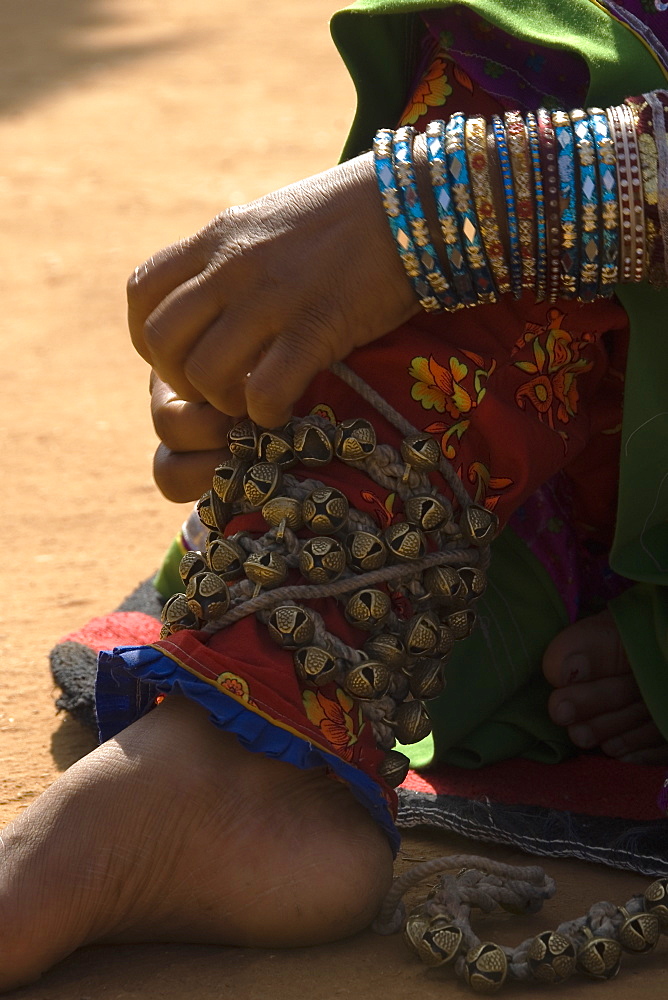 Rajasthani woman attaching bells to her feet for traditional dance, Rajasthan, India