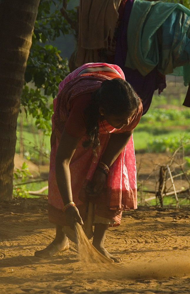 Local woman sweeping the area around the farmhouse, Gokarna, Karnataka, India