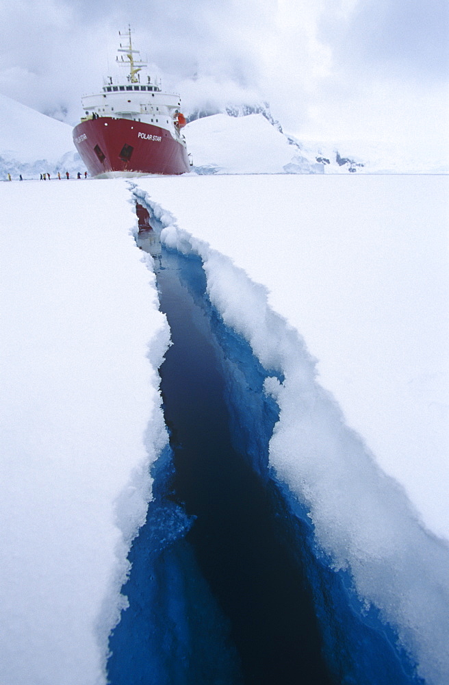 'Polar Star' ecotourism expedition ship with crack in 3m thich ice, created by the ship. Antartic Peninsula, Southern ocean.