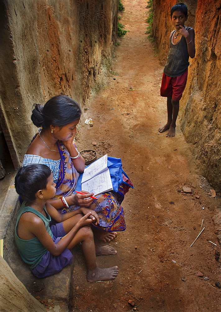 Mother teaching her child in a tribal village in India.