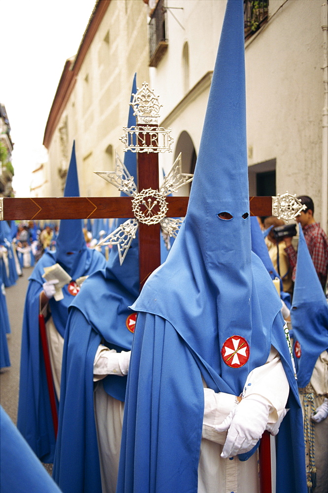 Hooded penitents around a cross in the Holy Week procession in Seville, Andalucia, Spain, Europe