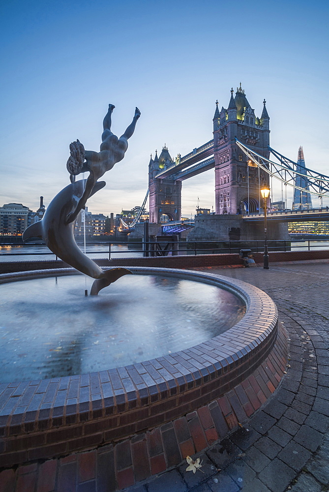 Girl with Dolphin fountain and Tower Bridge at night, St. Katharine's and Wapping, London, England, United Kingdom, Europe