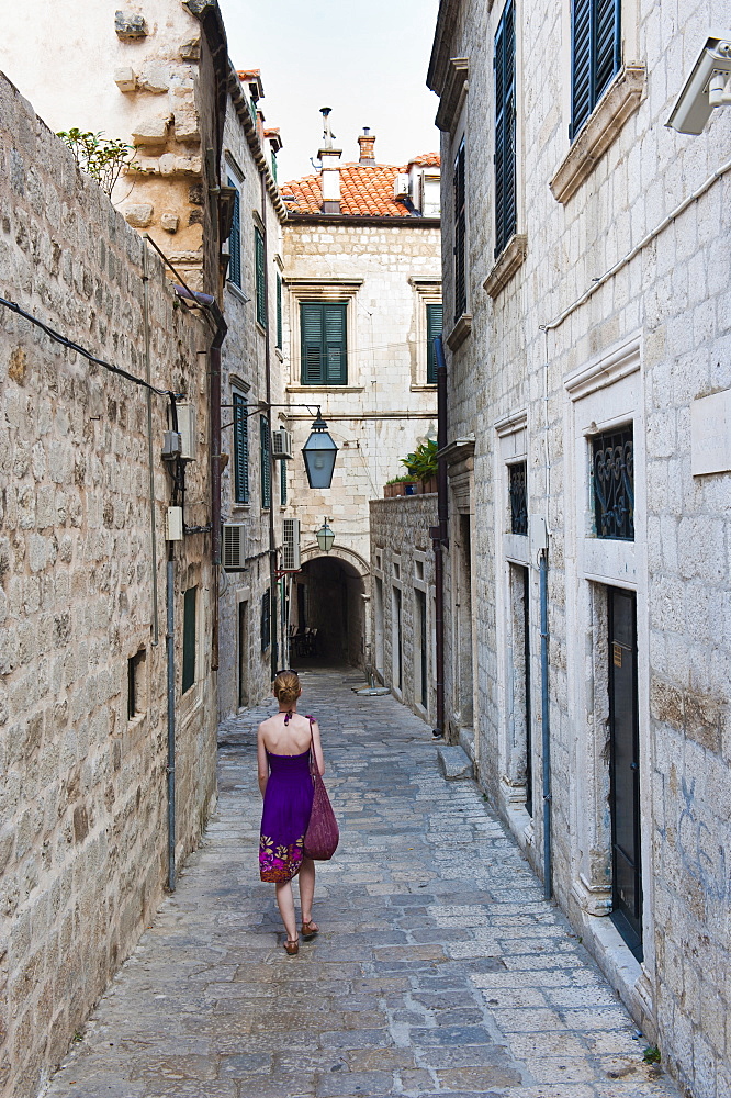 Dubrovnik Old Town, a tourist walking along a narrow side street, Dubrovnik, Croatia, Europe 