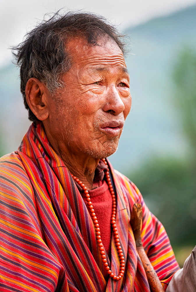 Portrait elderly Bhutanese man wearing prayer beads, Bhutan, Asia