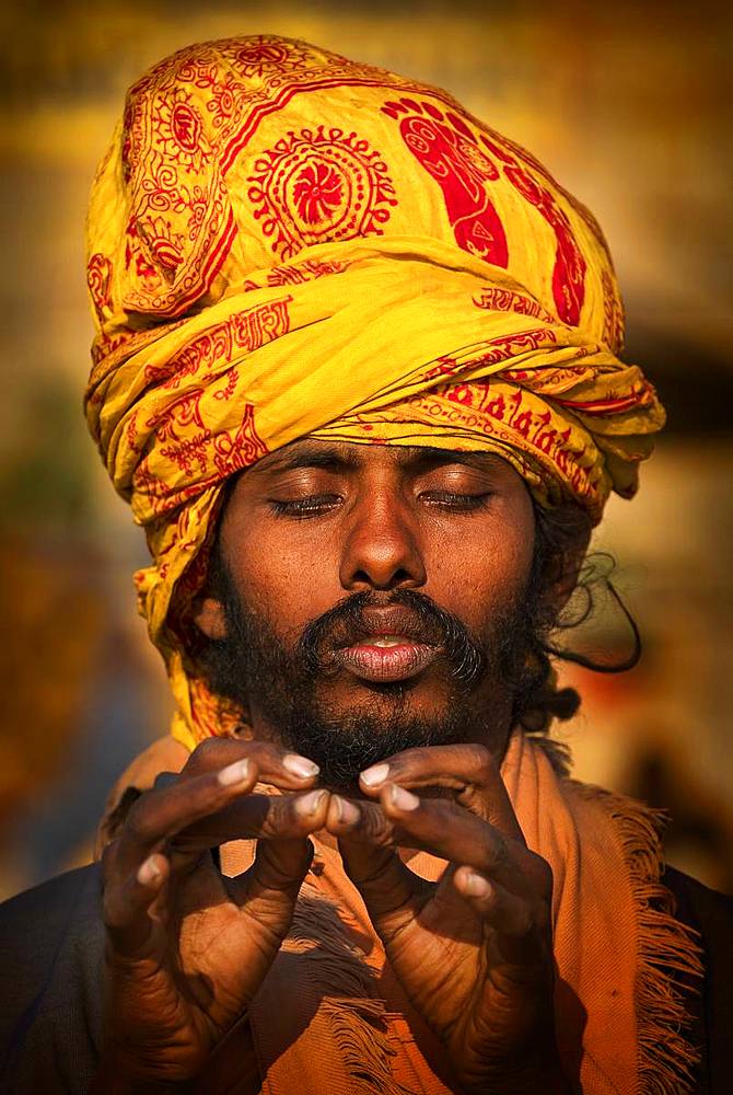 Portrait of sadhu meditating through hand yoga mudras on the ghats along the Ganges River, Varanasi, Uttar Pradesh, India, Asia