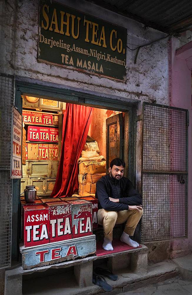 Portrait of an Indian man surrounded by tea tins in his shop, back alleyway near the ghats, Varanasi, Uttar Pradesh, India, Asia