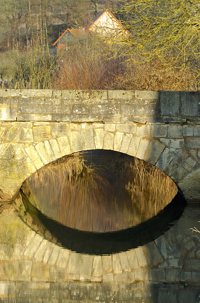 Old stone bridge with reflection at Salzboeden over the small river Salzboede near Giessen, Hesse, Germany