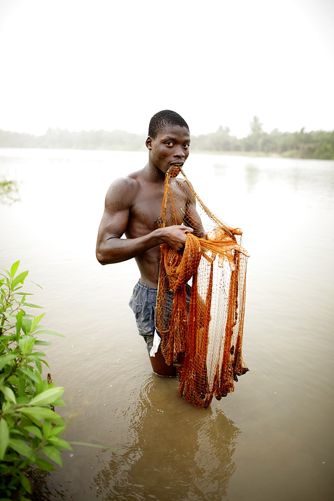 Young man fishing with cast net in river Mono, Agbanakin, near Grand-Popo, Mono Department, Benin