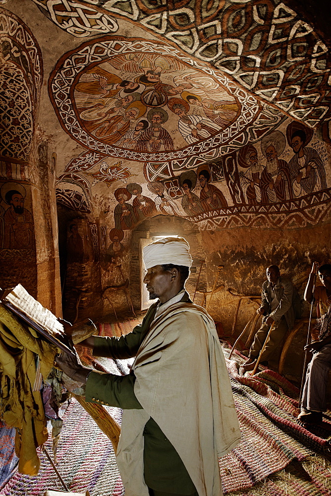 Priest reading in an old goatskin manuscript, Abuna Yemata Guh church with mural painting, Hawzien, Tigray Region, Ethiopia