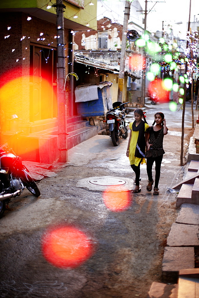 Girls walking along a street decorated with string of lights, Mysore, Karnataka, India