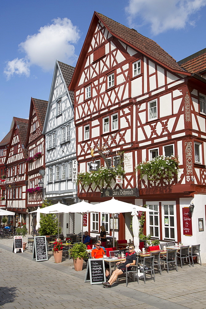 People sitting outside Gasthaus Zum Schmied restaurant near half-timbered houses in the old town, Ochsenfurt, Franconia, Bavaria