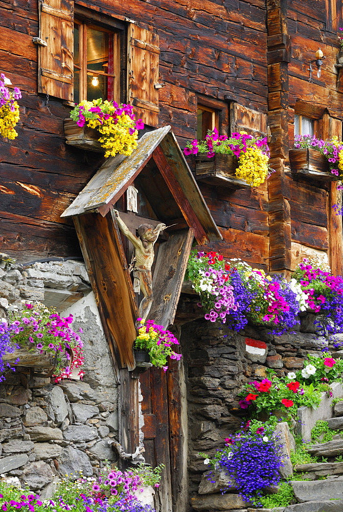 Crucifix and flower decoration at mountain farmhouse, valley Pfossental, Texel range, Oetztal range, South Tyrol, Italy