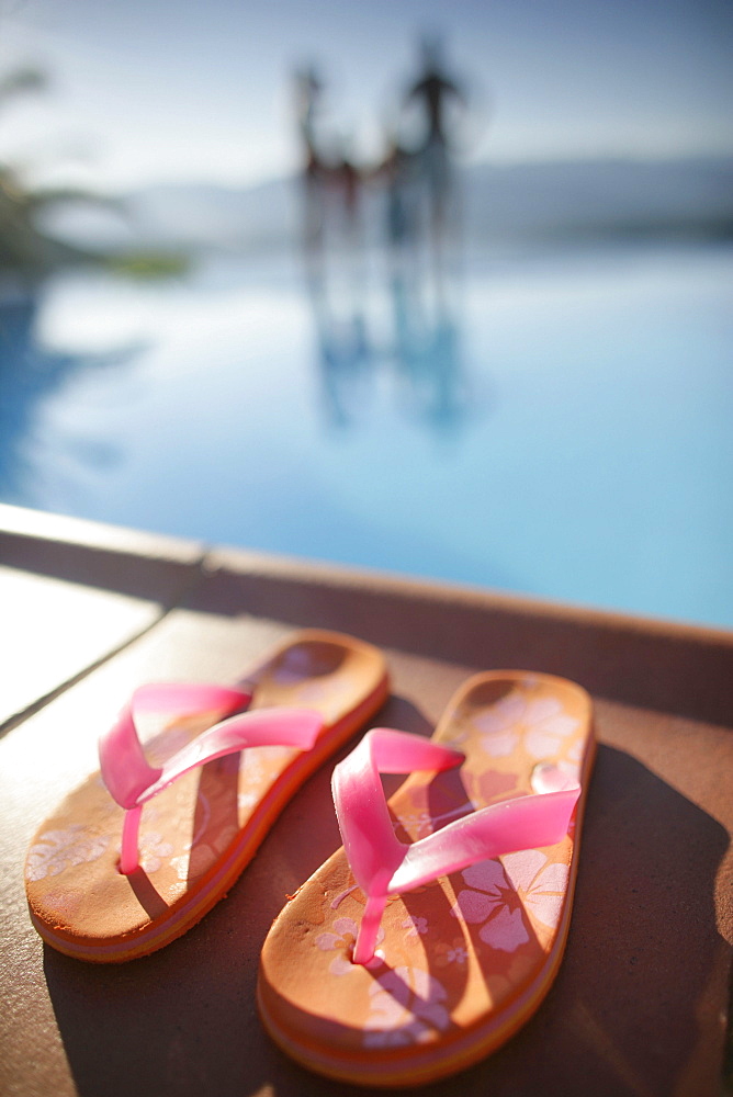 Family on poolside, focus on flip flops in foreground, Bay of Porto Vecchio, Southern Corse, France