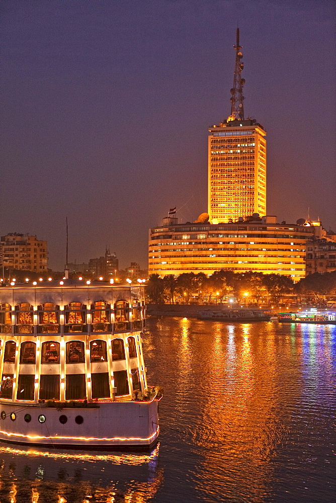 Illuminated ship on the Nile in front of the high rise building of the egyptian television center, Cairo, Egypt, Africa