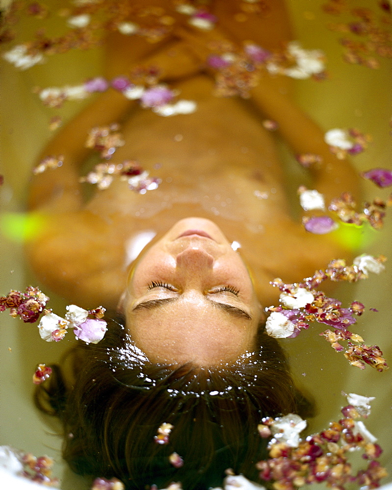 Woman relaxing in a bath filled with rose petals, Hotel Neuklostersee, Nakenstorf, Mecklenburg-Western Pomerania, Germeny, MR, PR