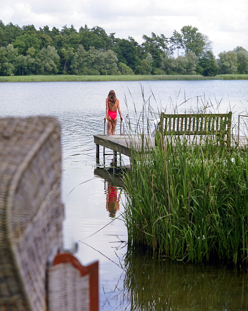 Woman standing on a jetty, Hotel Neuklostersee, Nakenstorf, Mecklenburg-Western Pomerania, Germany