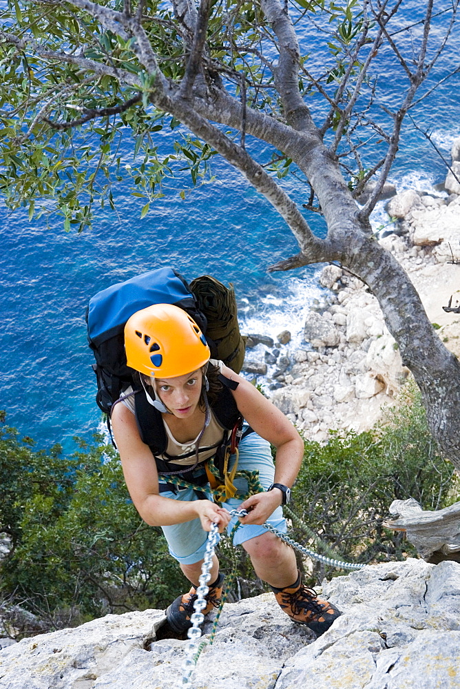 Young woman climbing, holding, chain, Il Sentiereo Selvaggio Blu, Golfo di Orosei, Sardinia, Italy, MR