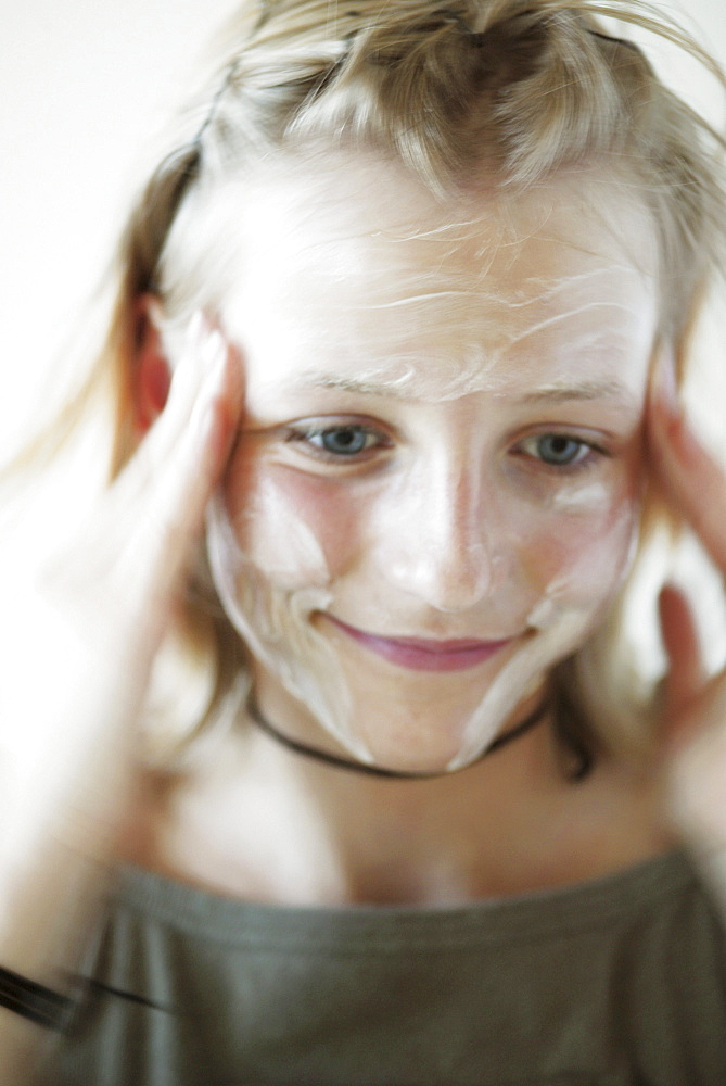 Teenage girl rubbing cream into face