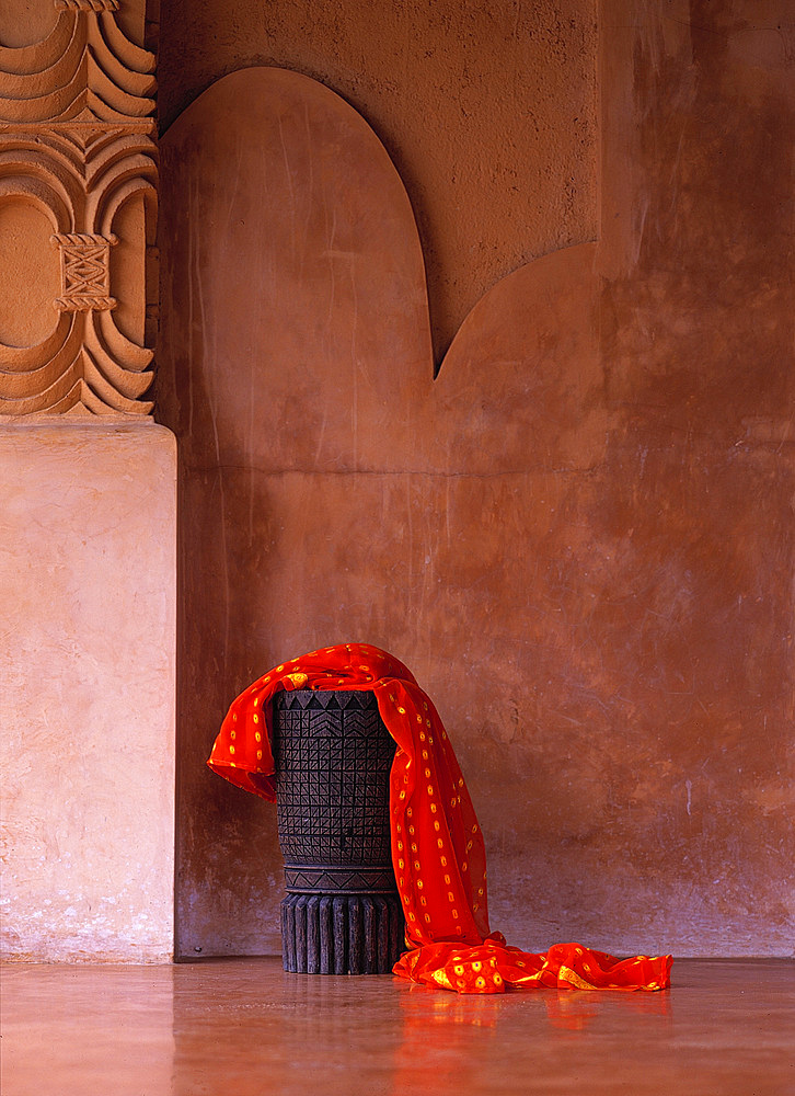 Sarong dressed over a wooden, carved stool set against a polished, decorated wall, Lombok, Indonesia.