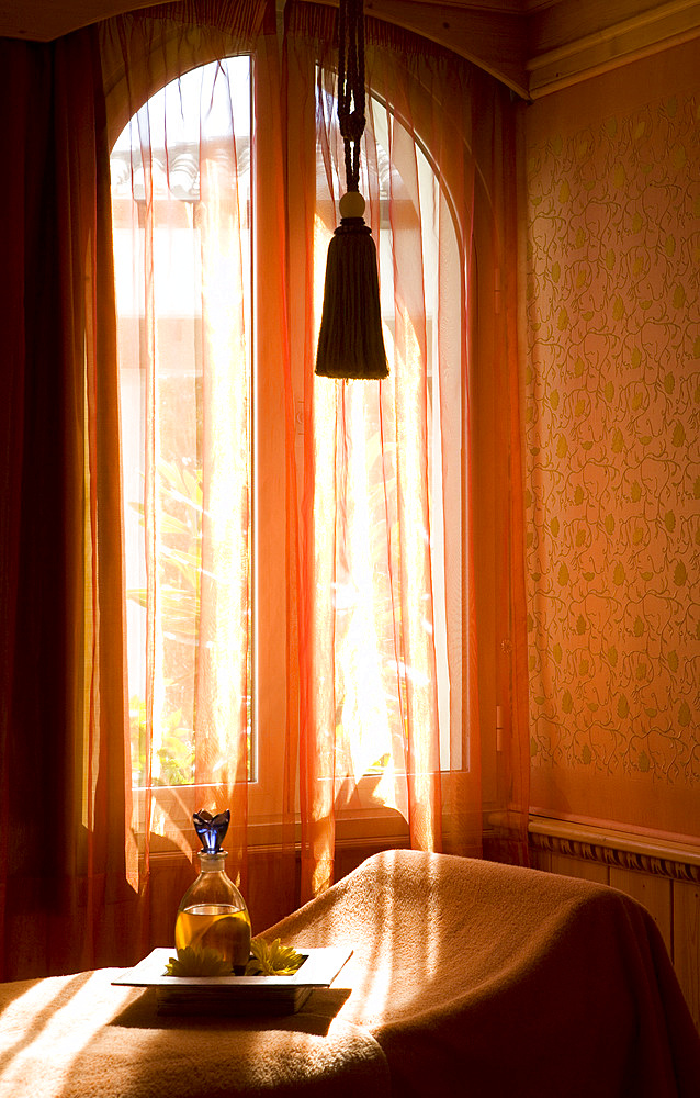 Interior shot of san oil bottle on tray, in a Spa treatment room kept in faded, orange hues. Madrid, Spain.