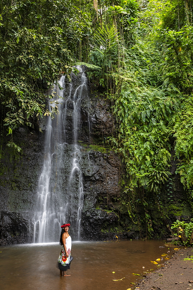 Beautiful young Tahitian woman in front of waterfall in 'The Water Gardens of Vaipahi', Teva I Uta, Tahiti, Windward Islands, French Polynesia, South Pacific