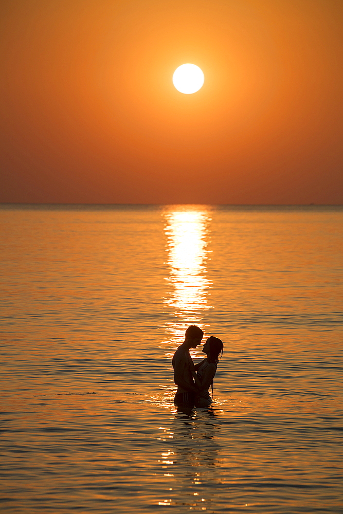 Silhouette of a romantic young couple in the water in front of Ong Lang Beach at sunset, Ong Lang, Phu Quoc Island, Kien Giang, Vietnam, Asia