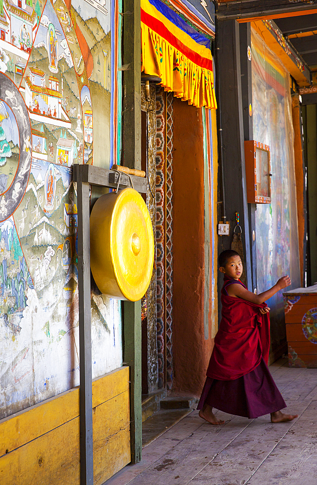 A boy monk, dressed in bright colors, shot inside a Bhutanese monistary. Bhutan.