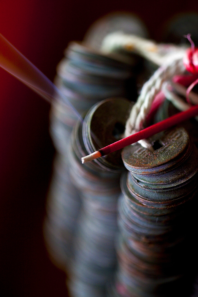 Ceremonial coins with a burning incense stick. Shot in Bali.