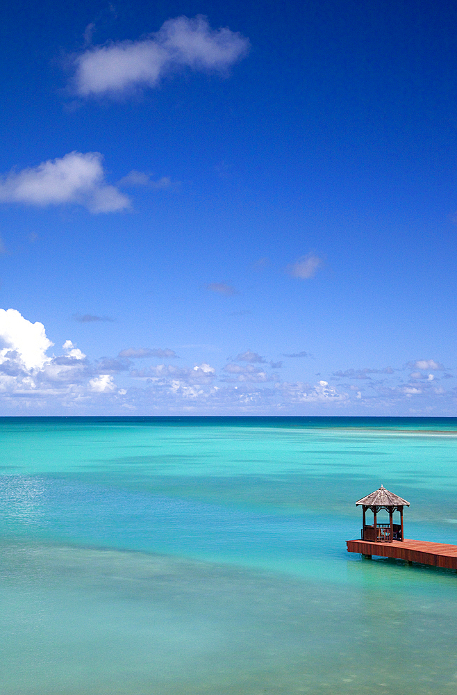 A dock with pavillion shot from the air, set in bright, turqiouse waters. Shot in Antigua.