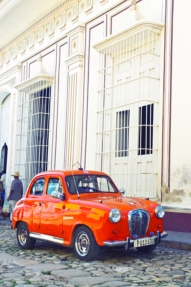 Classic red car in front of a white building in Trinidad, Cuba