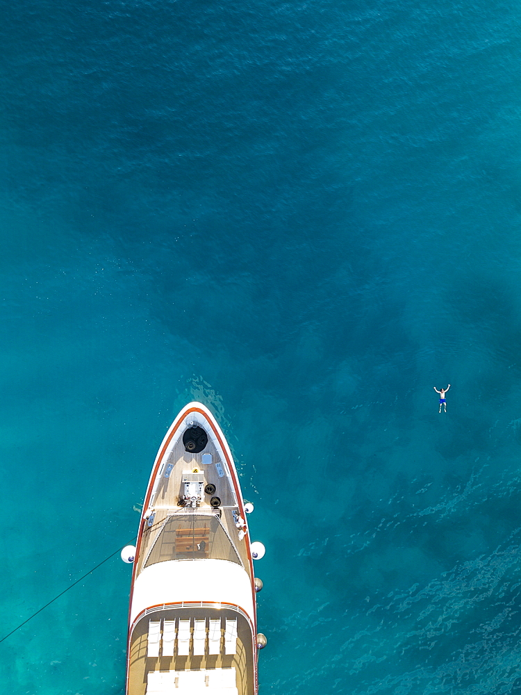 Aerial view of cruise ship with man who swims next to the bow in the water, near Kampor, Primorje-Gorski Kotar, Croatia, Europe