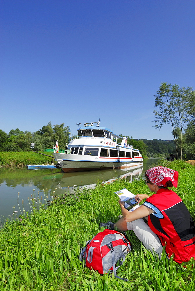 Woman sitting in meadow near river Danube while reading, Ardagger Markt, Lower Austria, Austria