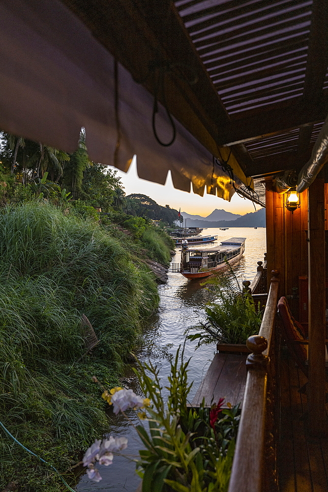 Side of river cruise ship Mekong Sun on river Mekong and longtail boat at dusk, Luang Prabang, Luang Prabang Province, Laos, Asia