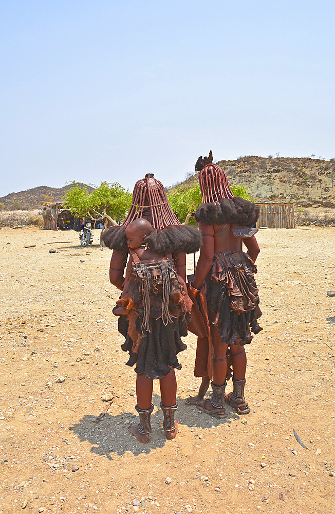 Angola; in the southern part of Namibe Province; two Muhimba women with their children; dressed in leather aprons; traditional hair styling