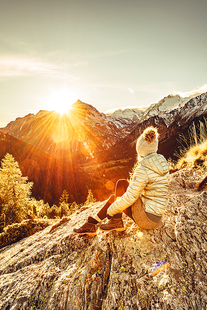 Woman sits on rocks in Maloja and enjoys the sunset, Engadin, Graubünden, Switzerland, Europe