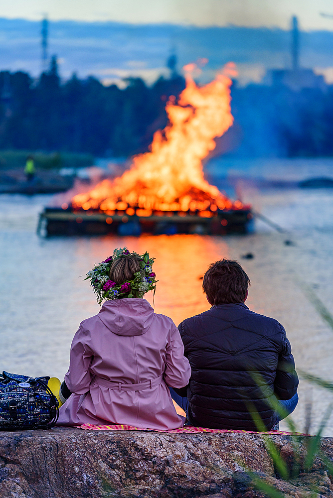 Couple looks at fire in lake, Midsummer festival in Seurasaari Open Air Museum, Helsinki, Finland