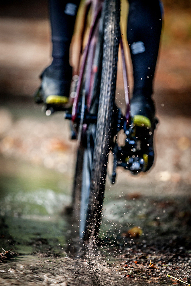 Autumn weather, Gravel biker drives through puddle