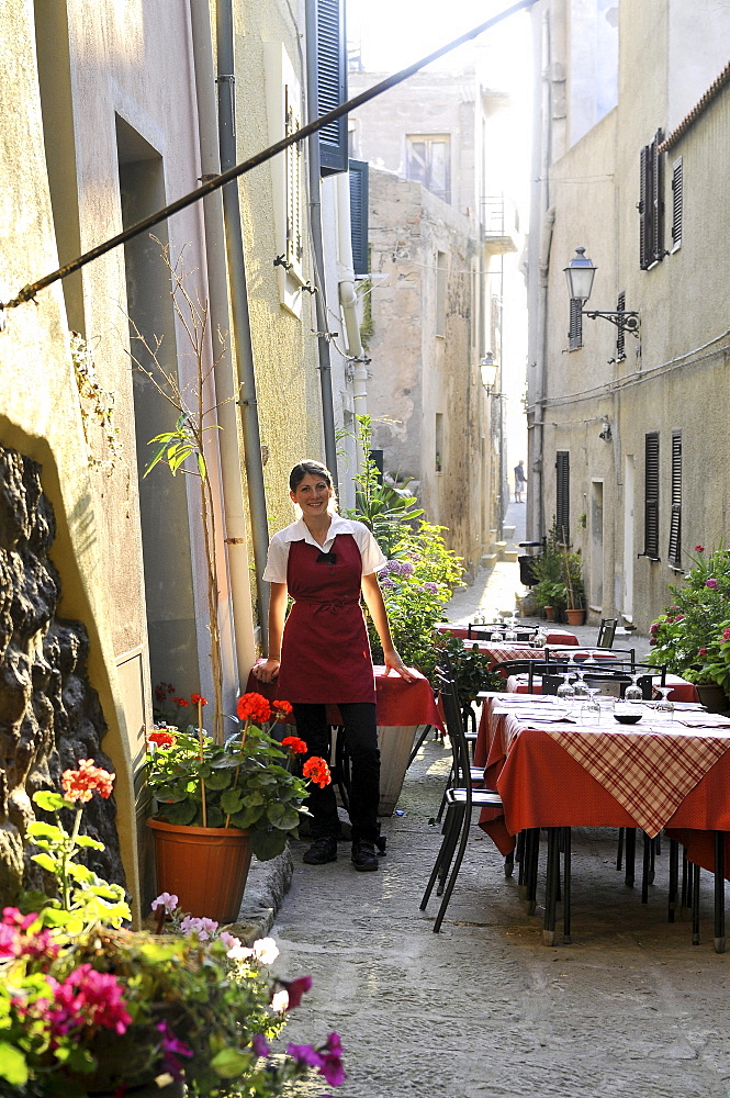 Waitress and tables of a restaurant at an alley, Castelsardo, Sardinia-north, Italy, Europe